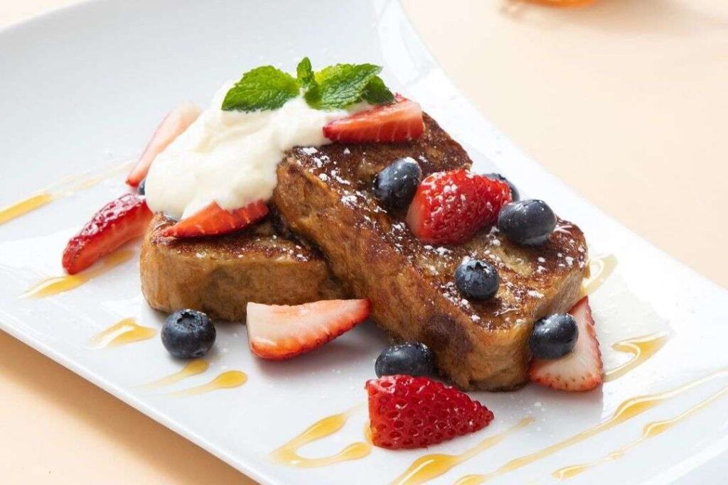 Crepes and Waffles Medellín French toast topped with strawberries, blueberries, whipped cream and honey