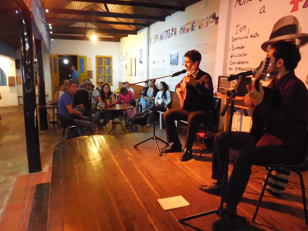 Tango singer and guitarist performing at Casa Gardeliana in Medellín with audience seated in background