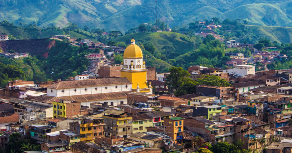 Aerial view of San Rafael Antioquia town with distinctive yellow-domed church and green hillside backdrop