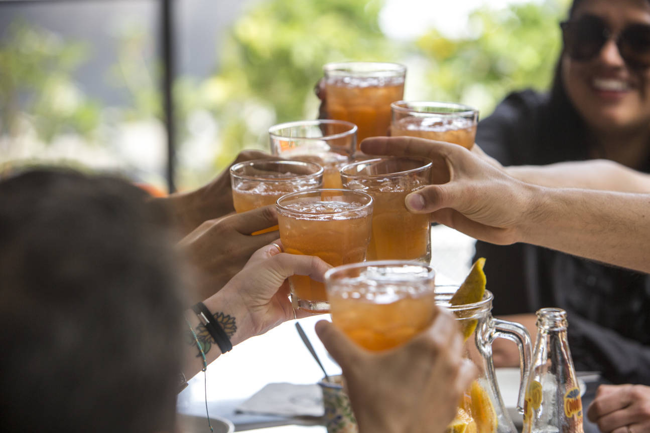 Group of food tour participants clinking glasses of aguapanela cocktails at a Medellín restaurant