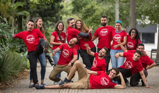 Real City Tours Medellín team photo with guides in red shirts posing playfully outdoors in a park