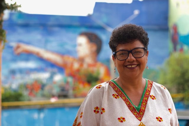 Comuna 4 local guide smiling in front of a colorful street mural in Medellín Colombia