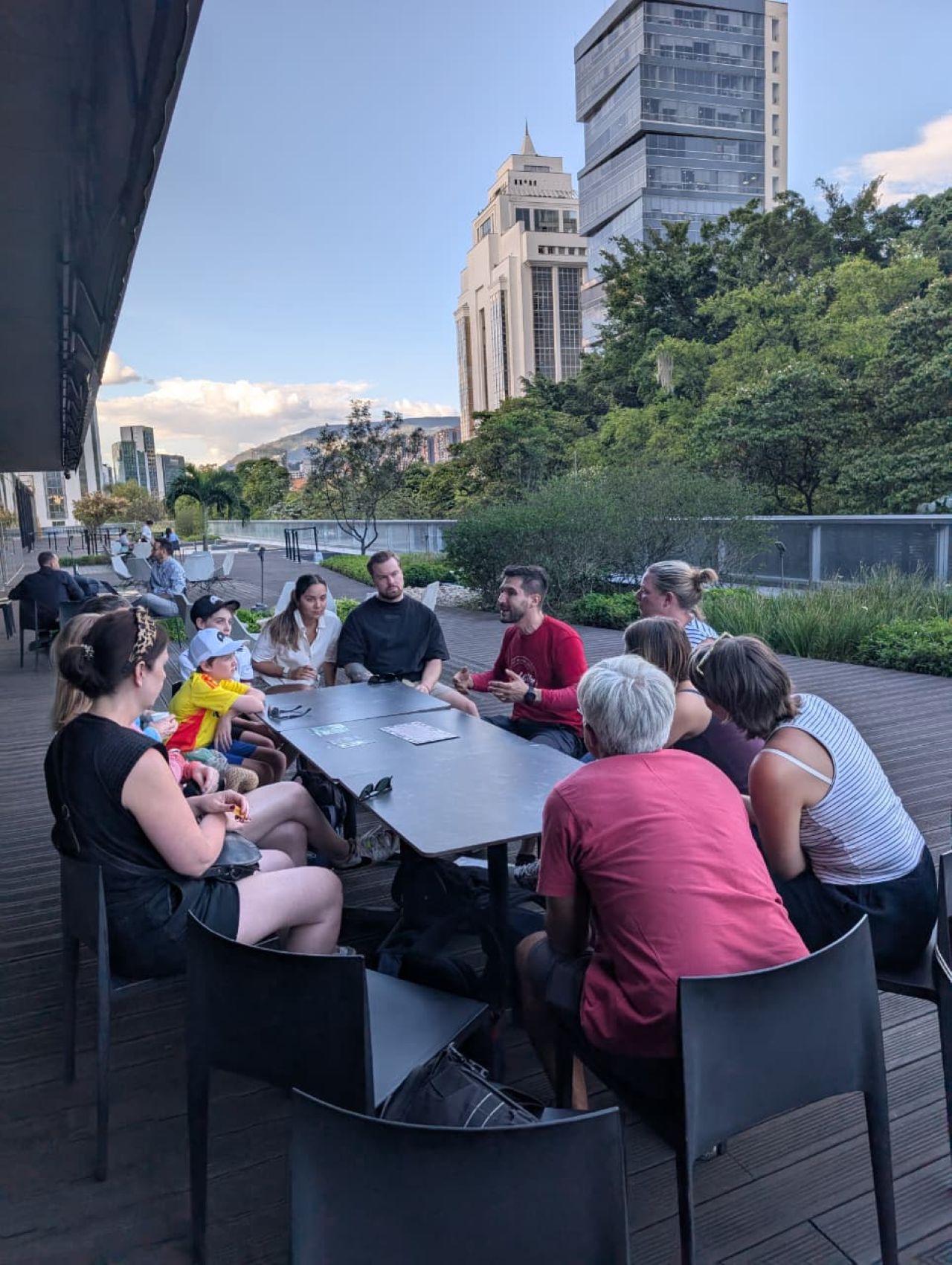 Real City Tours guide and tourist group seated at a rooftop terrace table with Medellín skyline views