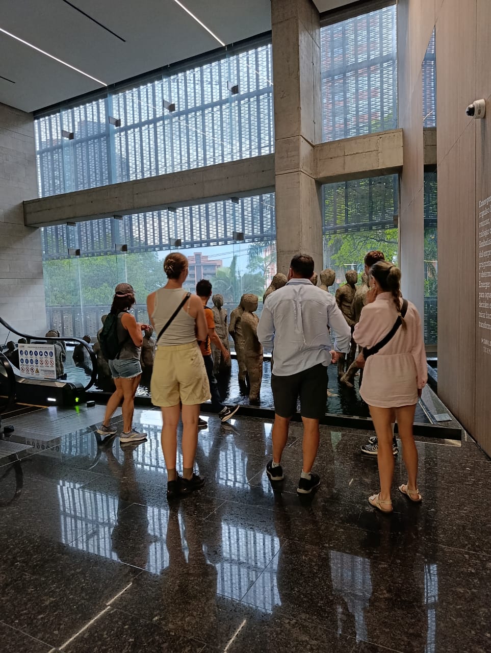 Tourists viewing a large bronze sculpture installation of human figures at a museum in Medellín Colombia